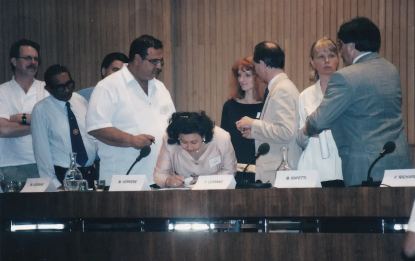 A signatory signs the Charter in the middle of a group of delegates.