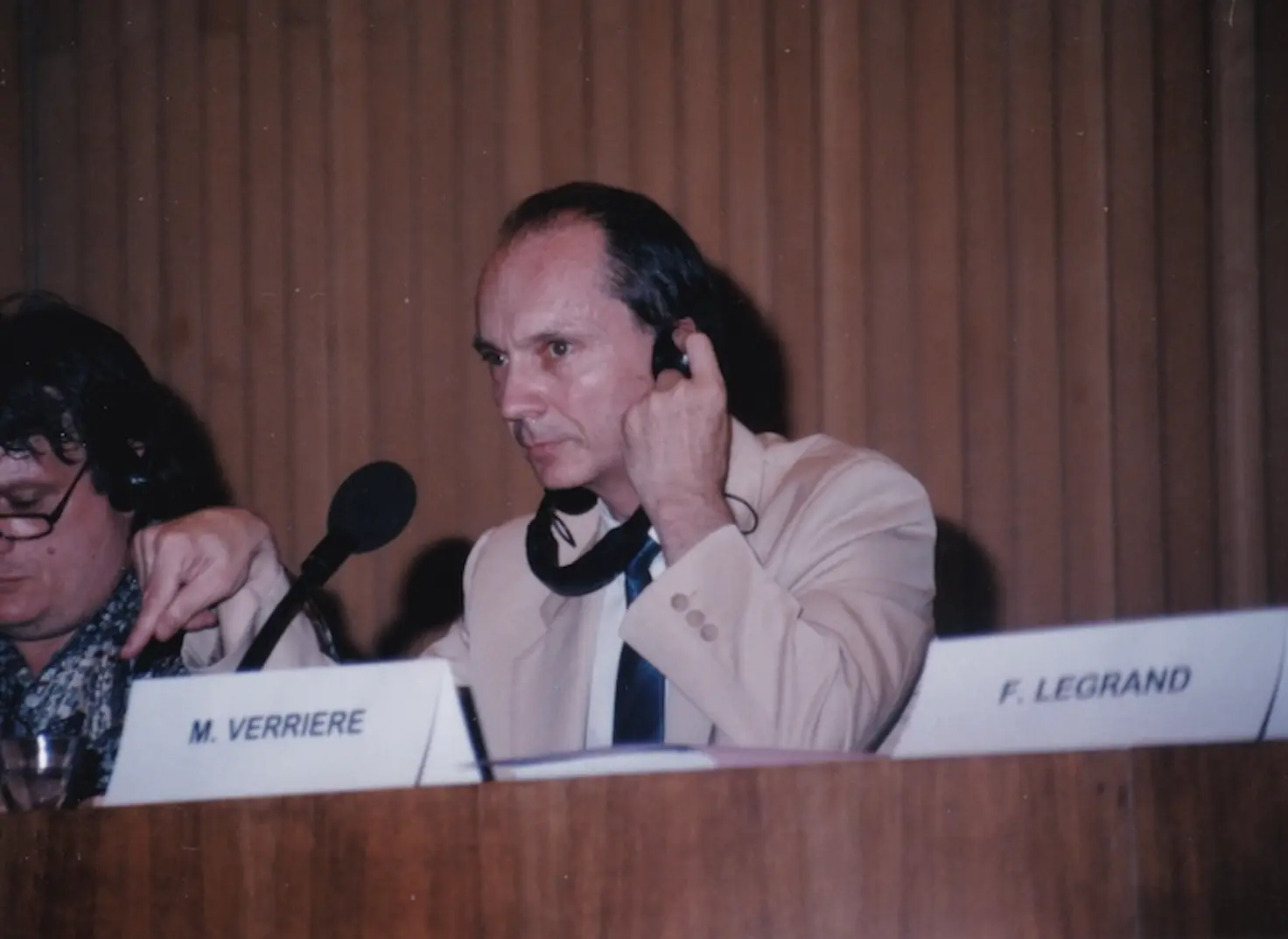 Marc Verrière, earpiece in his ear, at the official table behind his name card.
