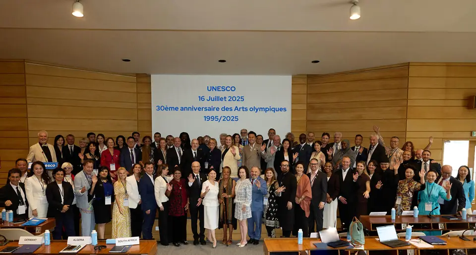 Some seventy representatives pose as a group in a UNESCO conference room, in front of a screen reading: “UNESCO, 16 juillet 2025, 30e anniversaire des Arts olympiques, 1995/2025”.