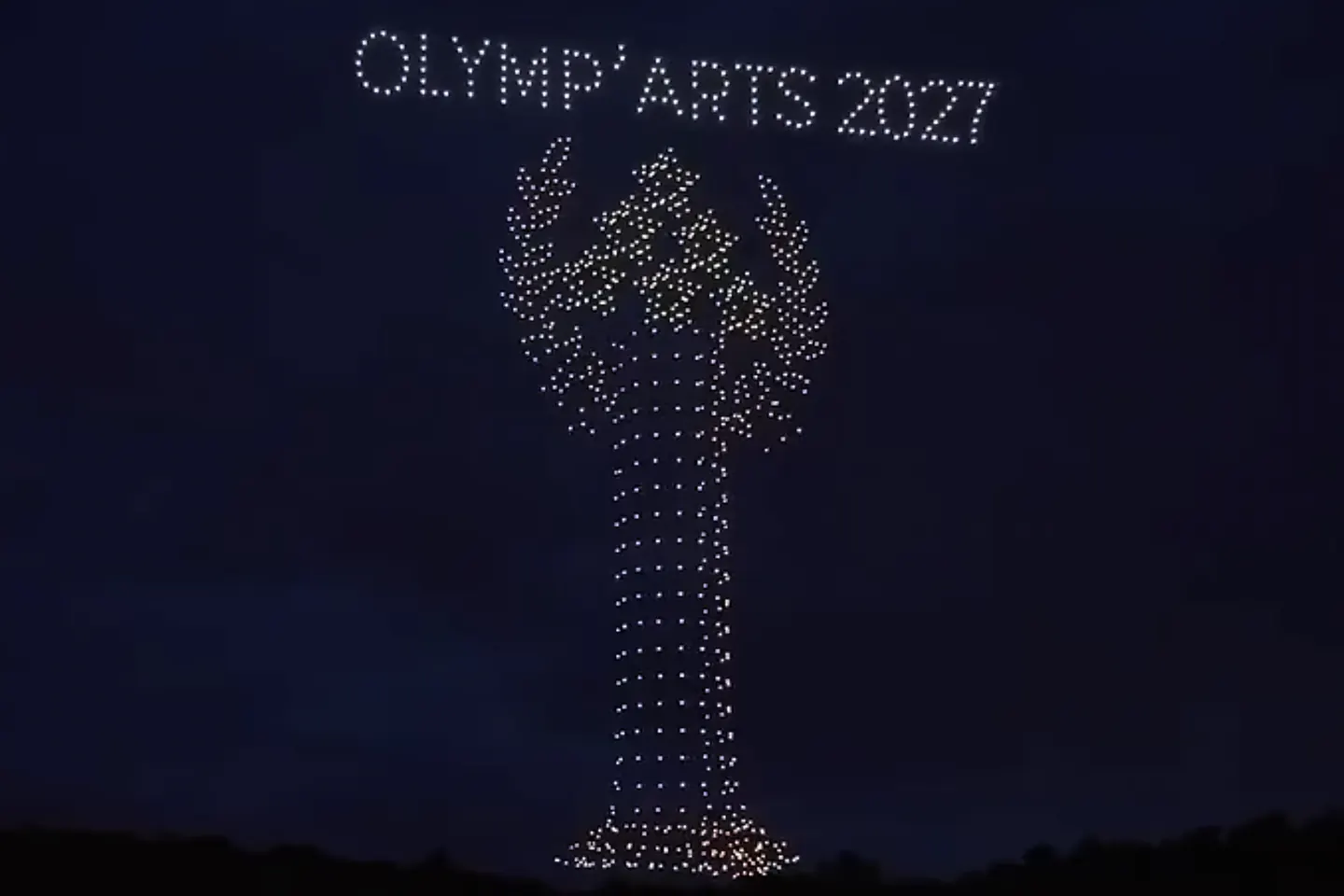 In the night sky, hundreds of glowing drones draw a trophy beneath the words “OLYMP’ARTS 2027”.